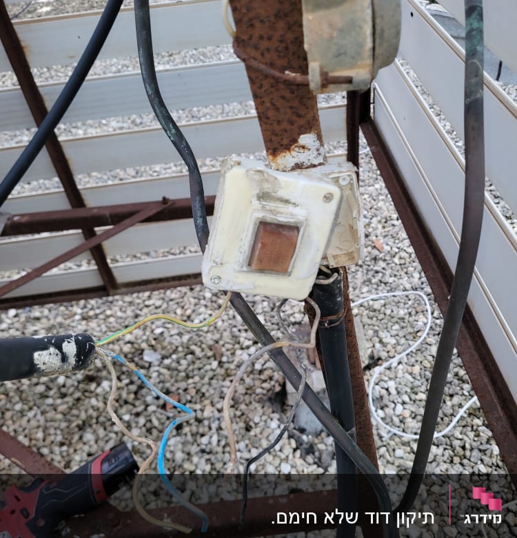 חוטי חשמל חשופים ומקדחה אדומה על הקרקע